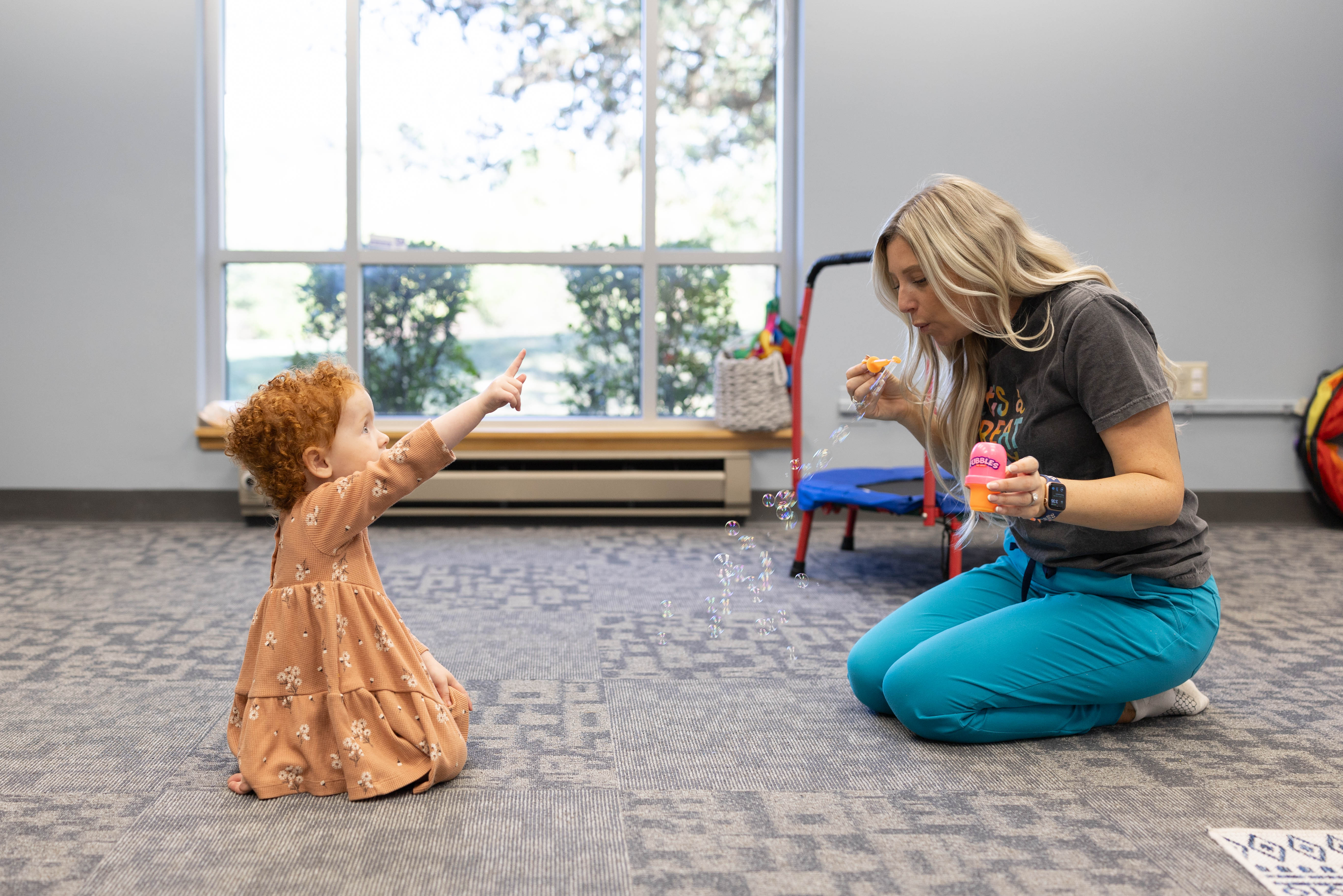 SLP blowing bubbles during a therapy session with a toddler
