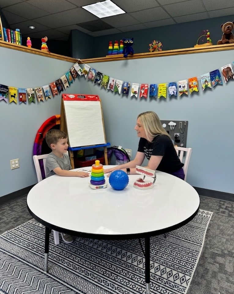 SLP working with a child at a table decorated with books and toys