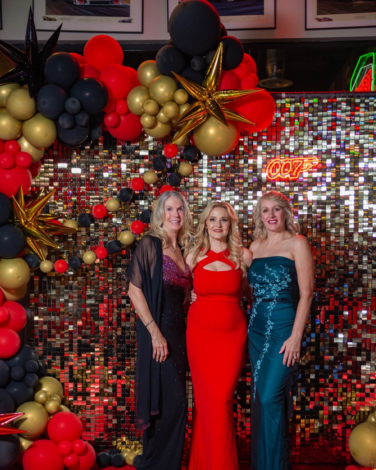Guests in gowns at a balloon and sequin backdrop at a milestone birthday