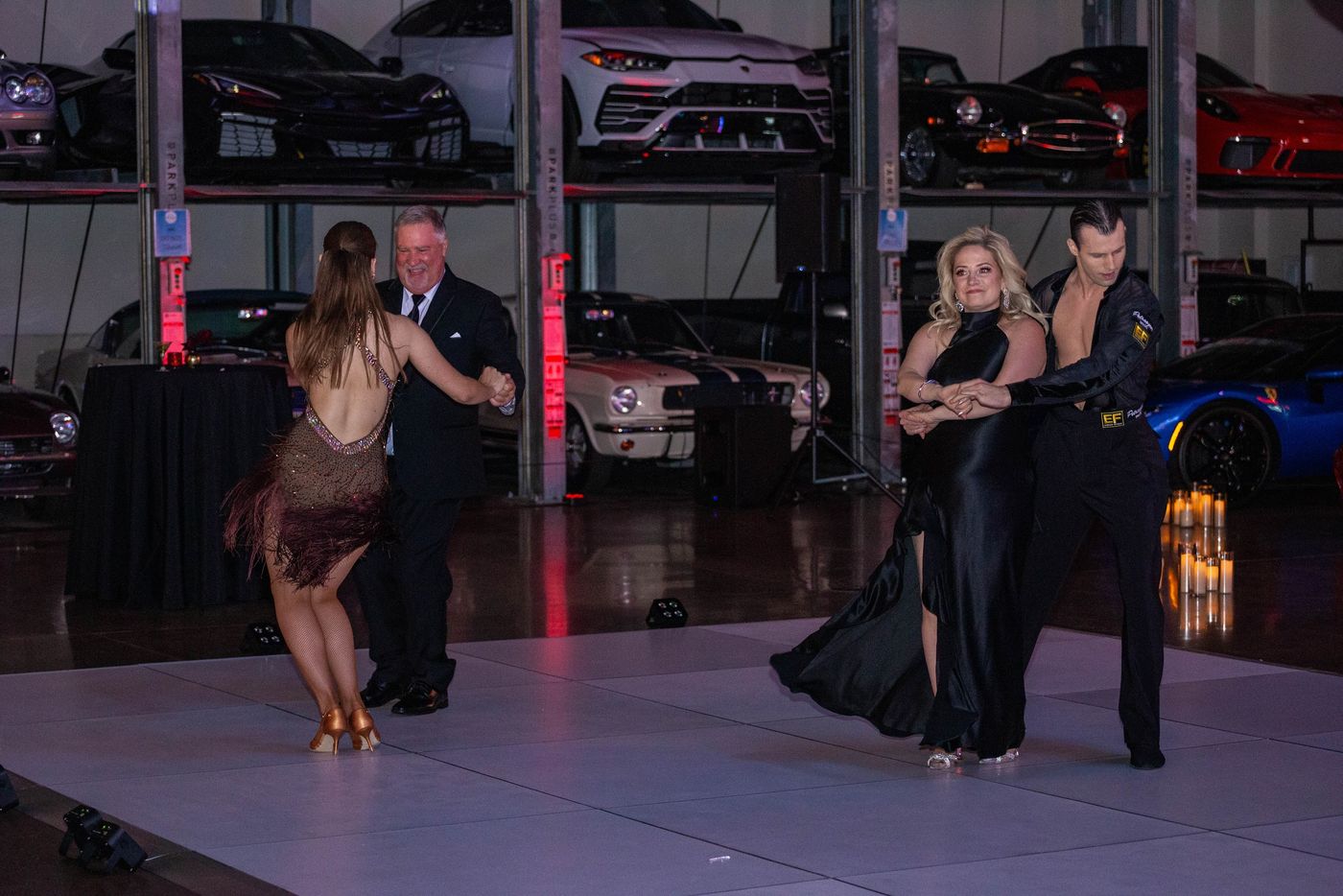 Guests dancing on a white floor among vintage cars