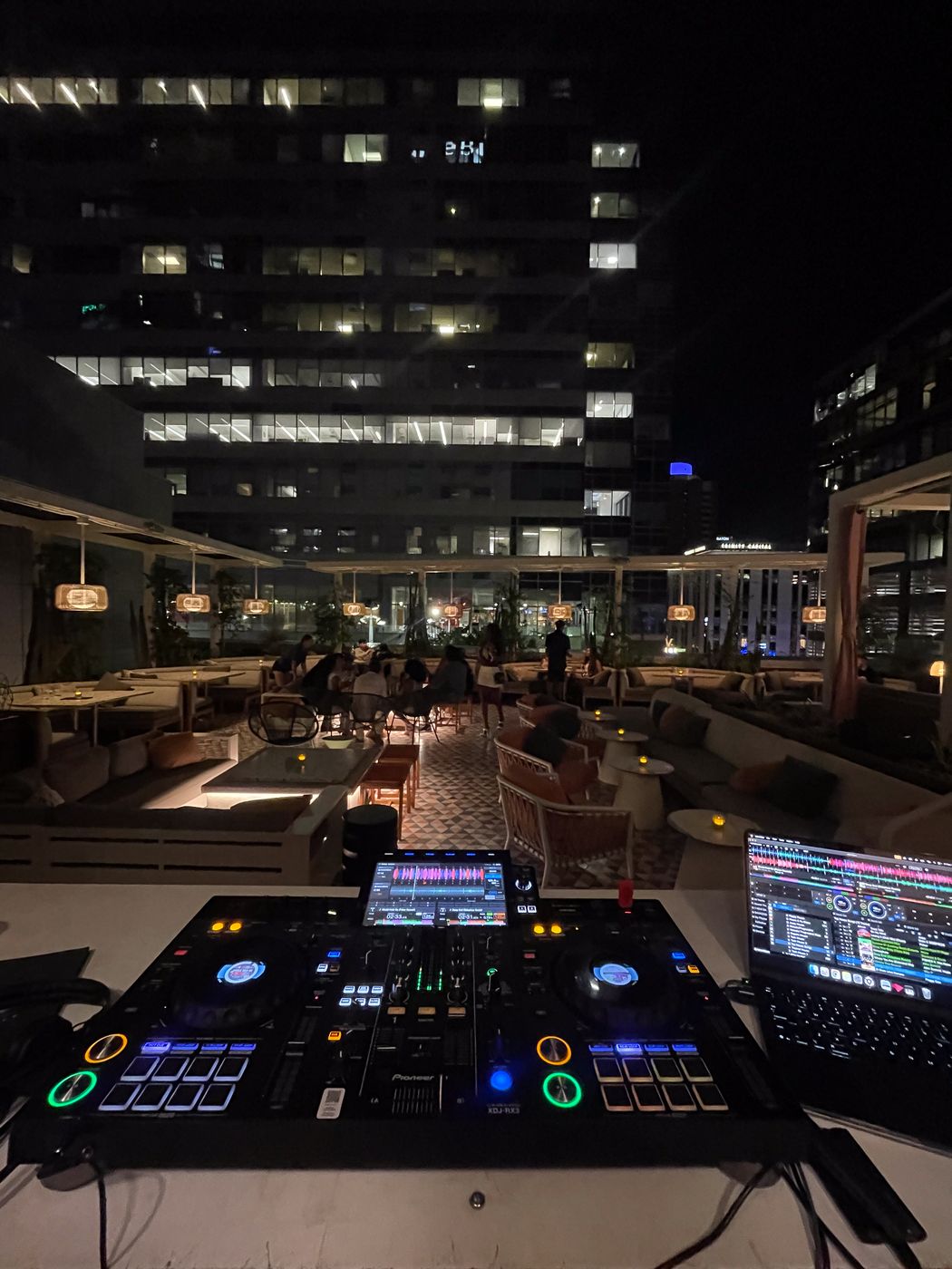 Rooftop DJ setup at night with city lights