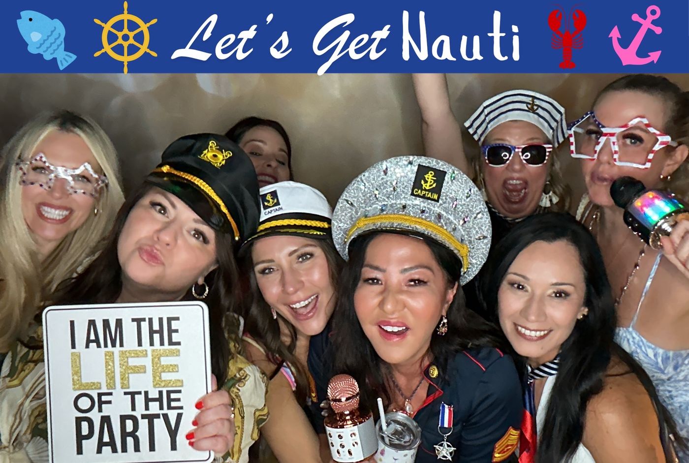 Friends in captain hats laughing under a Let's Get Nauti banner