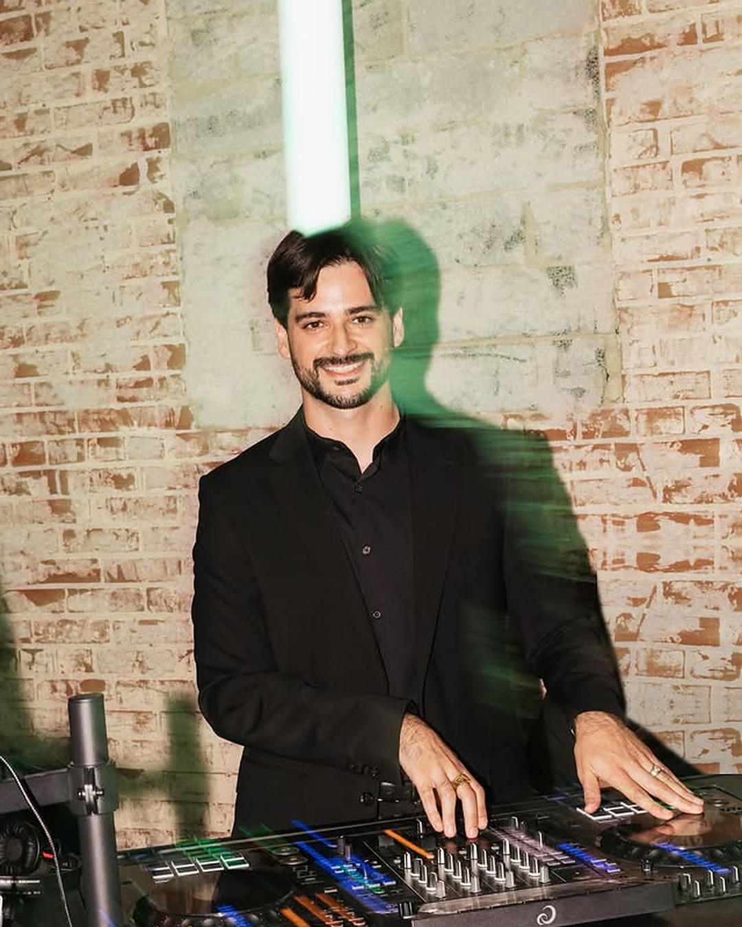 Erik smiling at the DJ booth with a soft motion blur of the night behind him