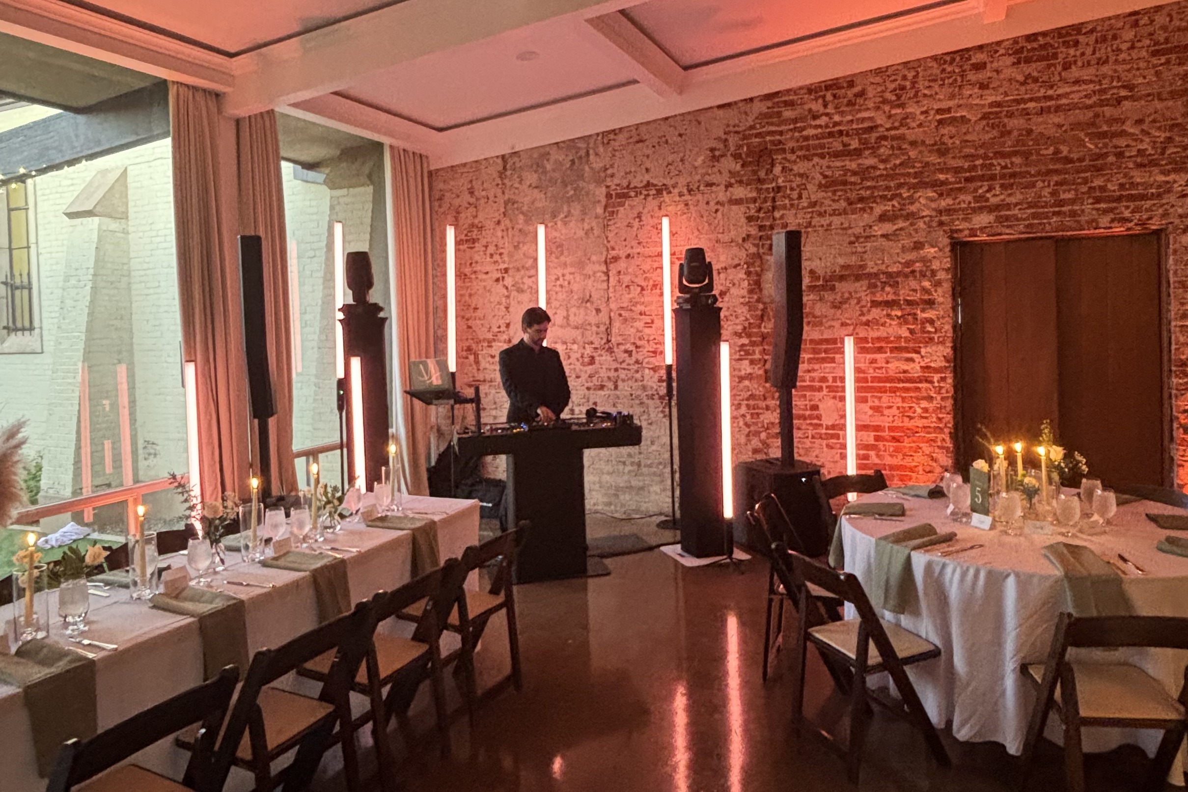 DJ booth tucked in the room corner with warm tube lighting.