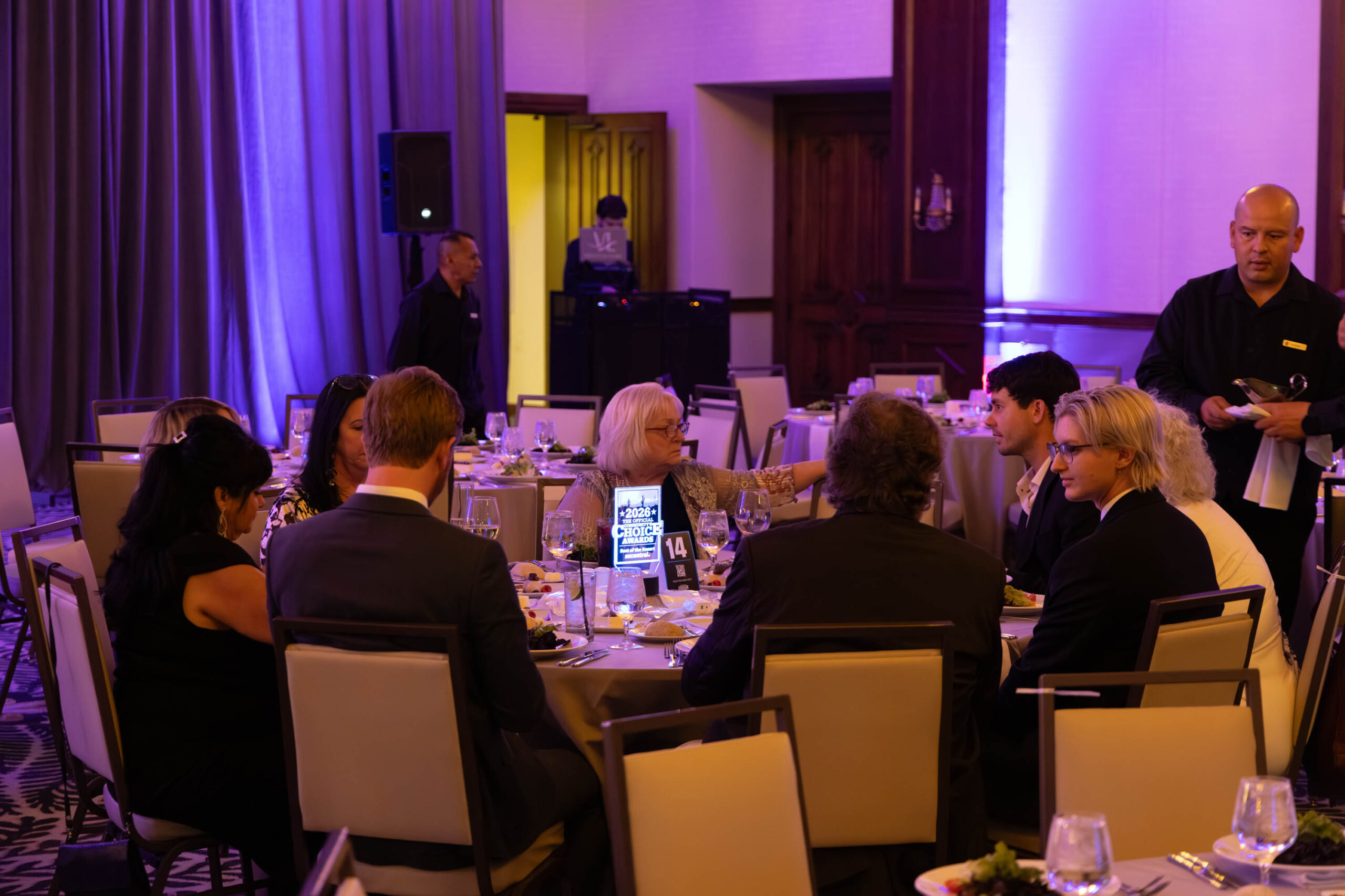 DJ booth behind a table of guests at a corporate awards dinner.