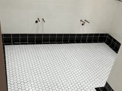 Shower floor with black and white hexagonal tiles and matching black wall tiles, creating a classic and stylish bathroom design.