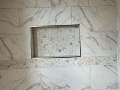 Custom marble shower with a hexagonal mosaic tile niche and accent strip, adding a touch of elegance to a bathroom design.