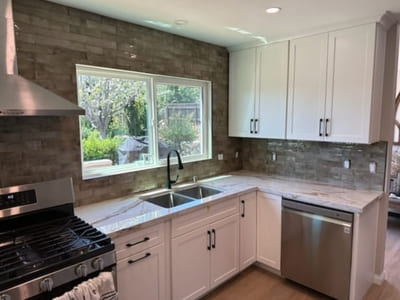 Kitchen backsplash with glossy brown subway tiles, offering a rustic yet modern design, paired with white cabinetry and large windows for natural light.