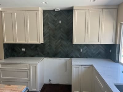 Kitchen with a dark herringbone tile backsplash and light cabinetry, offering a stylish contrast and modern appeal.