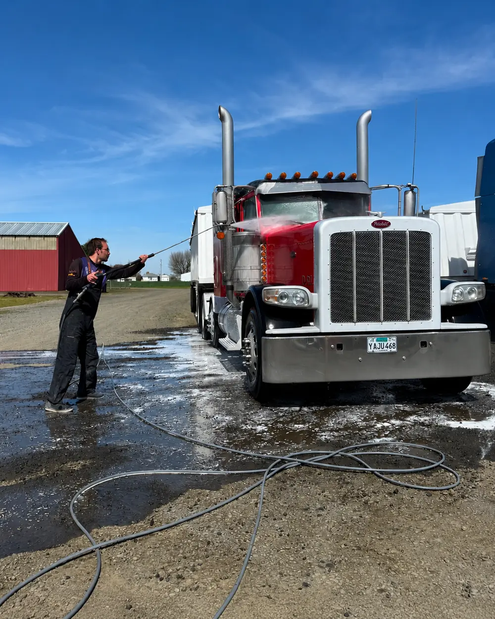 Grime Be Gone technician pressure washing a red semi truck in Salem, OR