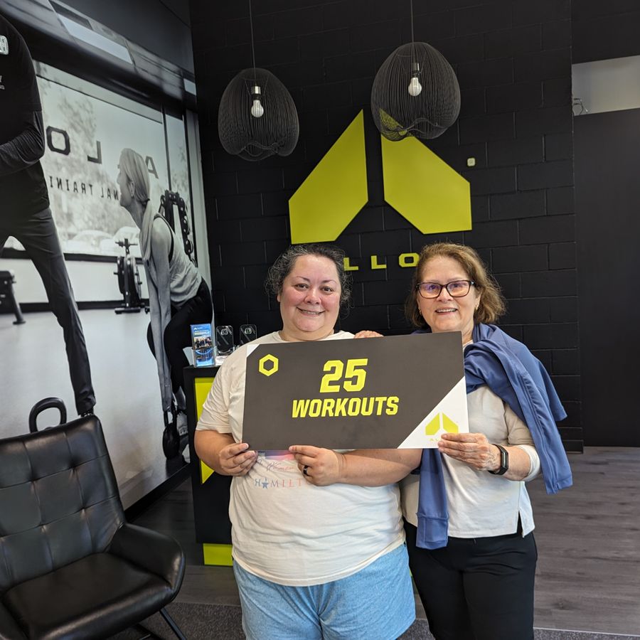 Two Alloy Woodinville members holding a 25 workouts milestone sign