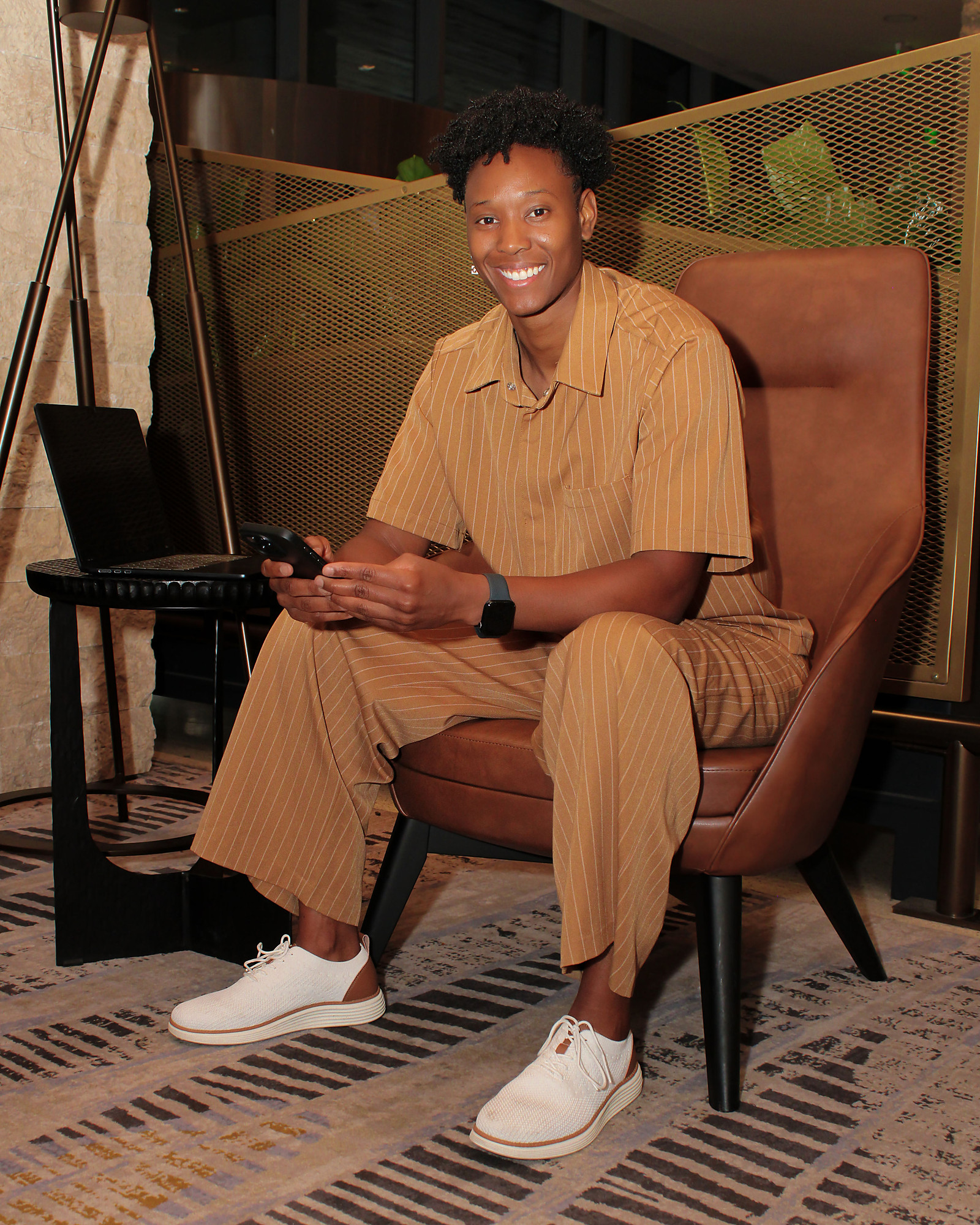 Earnie Williams working from a lounge chair with a phone and laptop
