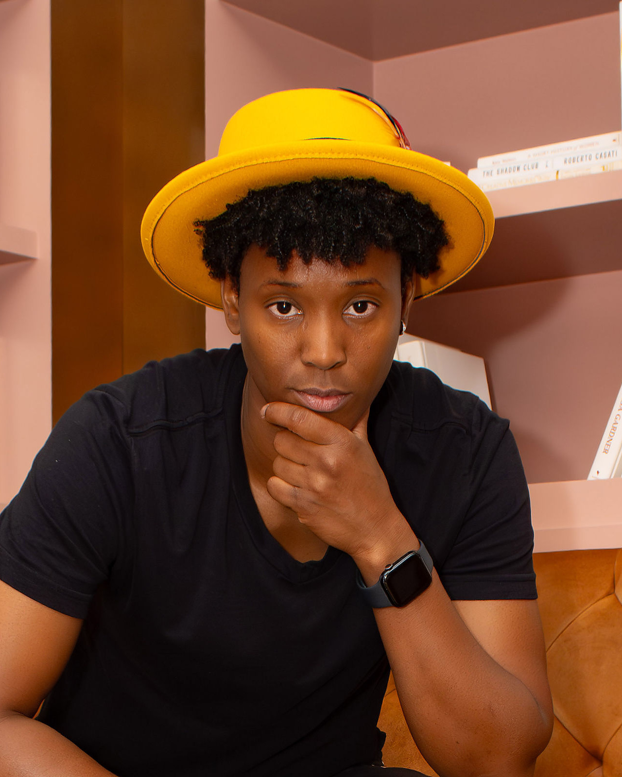 Earnie Williams in a gold hat and black tee, hand on chin, thinking