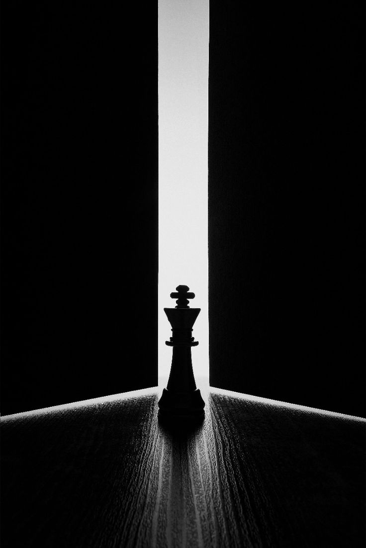 Un roi d’échecs devant une porte entrouverte, dans un rai de lumière.
