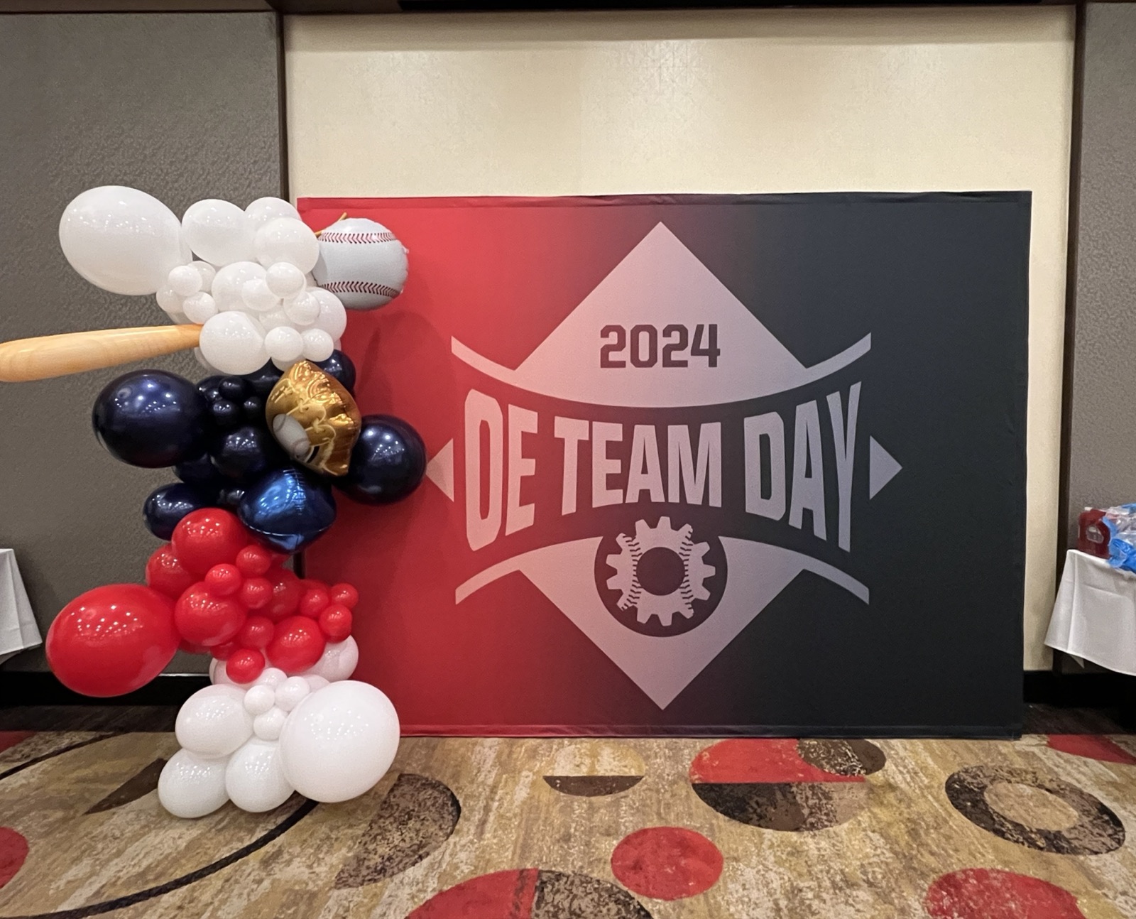 OE Team Day 2024 backdrop banner with baseball-themed balloon arch decor