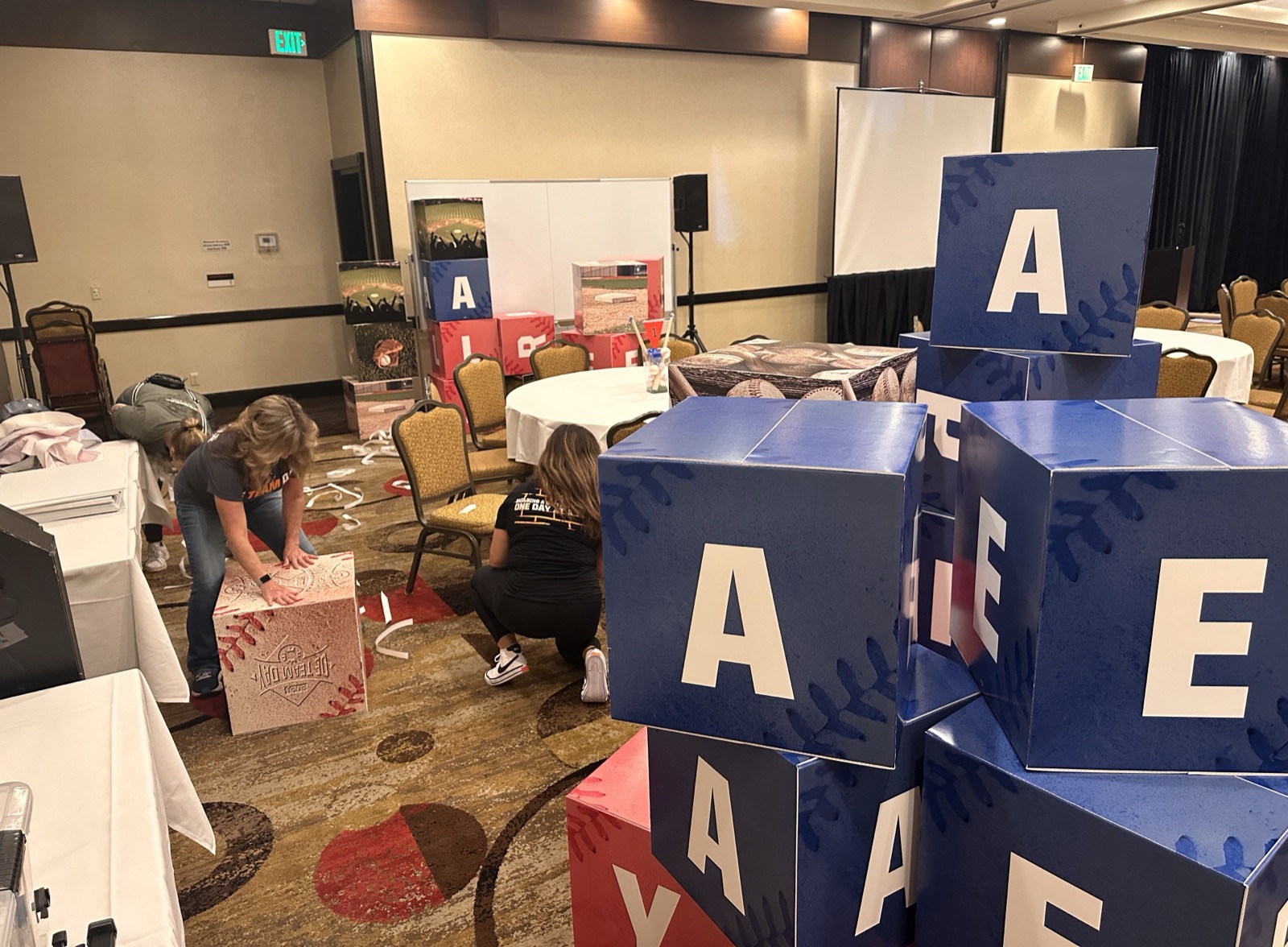 Team members setting up oversized OE Team Day letter cube decor pieces