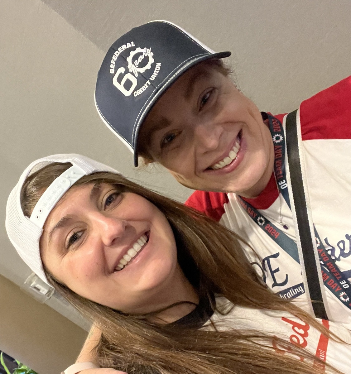 Ciara Pimentel smiling with a former OE Federal teammate at OE Team Day 2024, both wearing OE Federal branded caps and Team Day jerseys