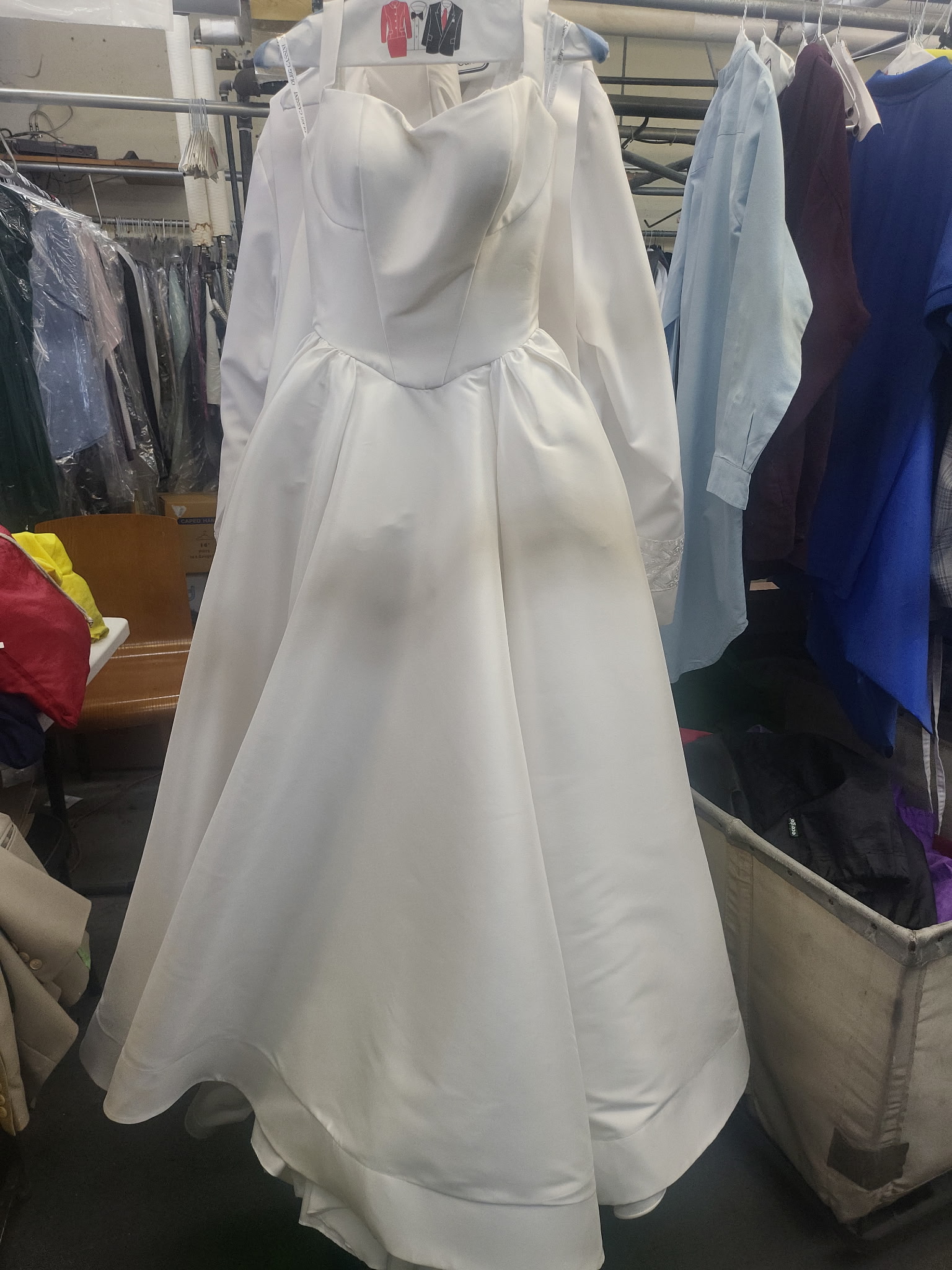 A long-sleeved lace wedding gown on a hanger in the shop