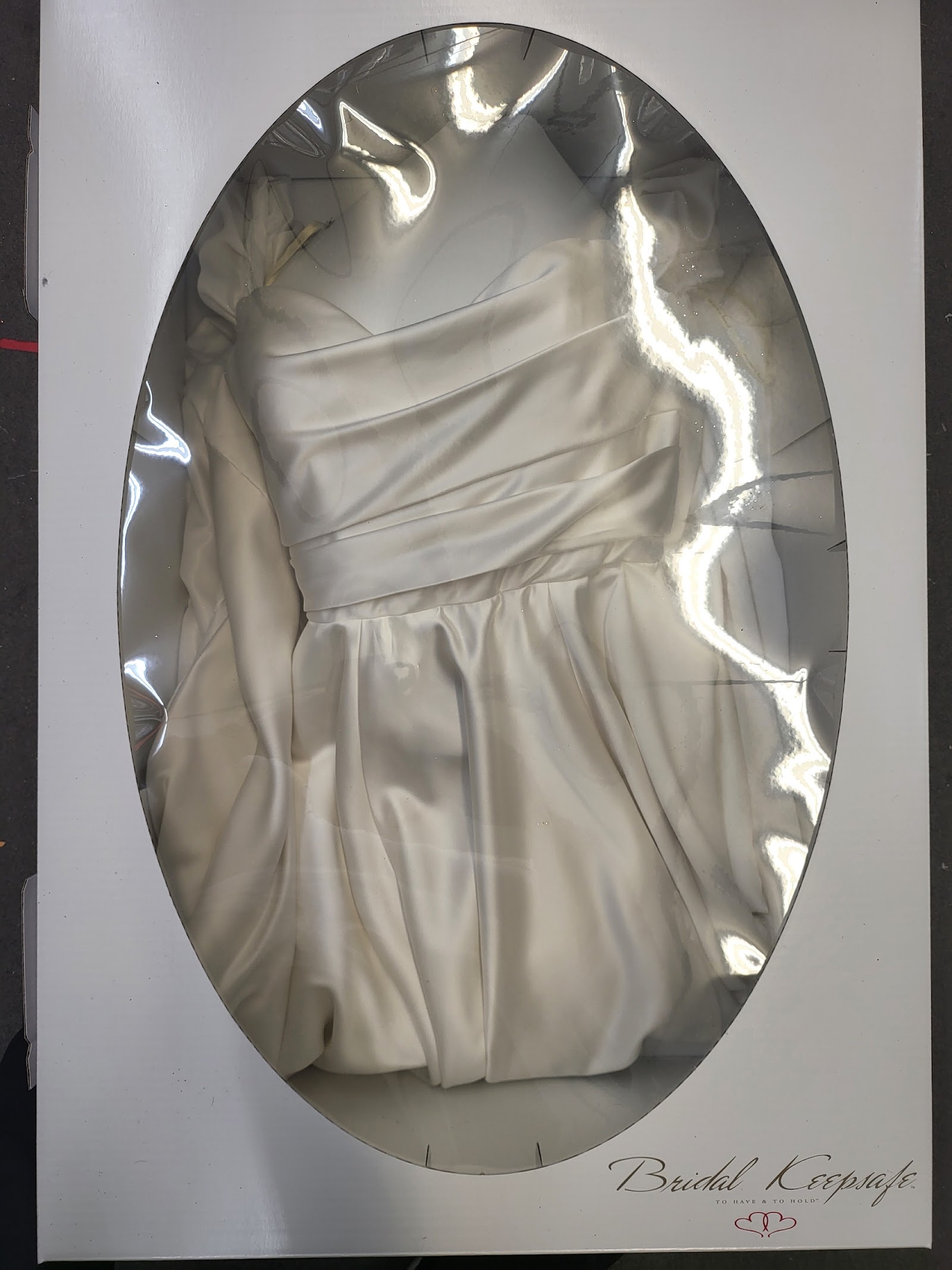 A wedding gown sealed in a wedding preservation box with a clear oval window, Lucy's Cleaners Glendora
