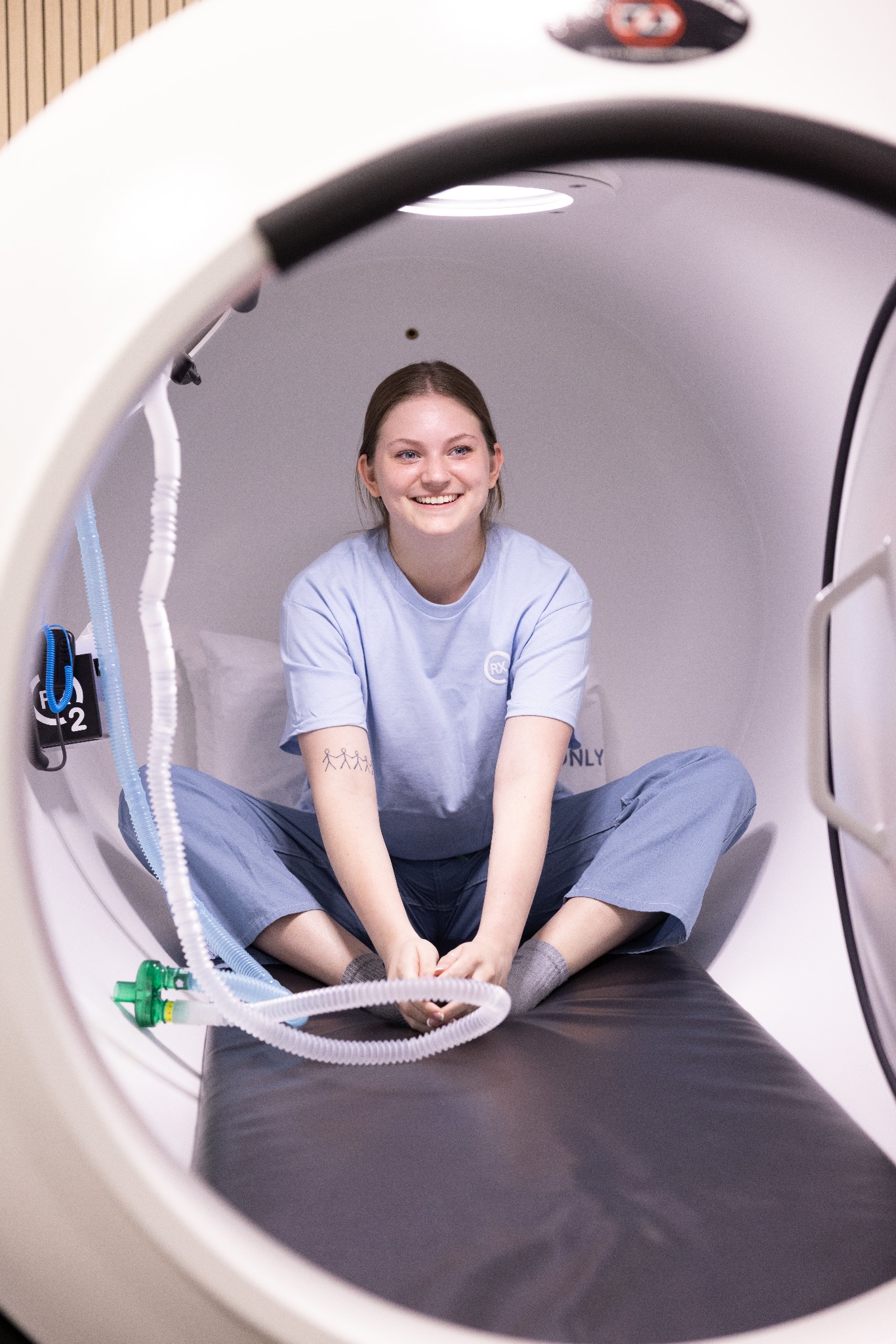 A staff member seated inside an open hyperbaric chamber during a demonstration