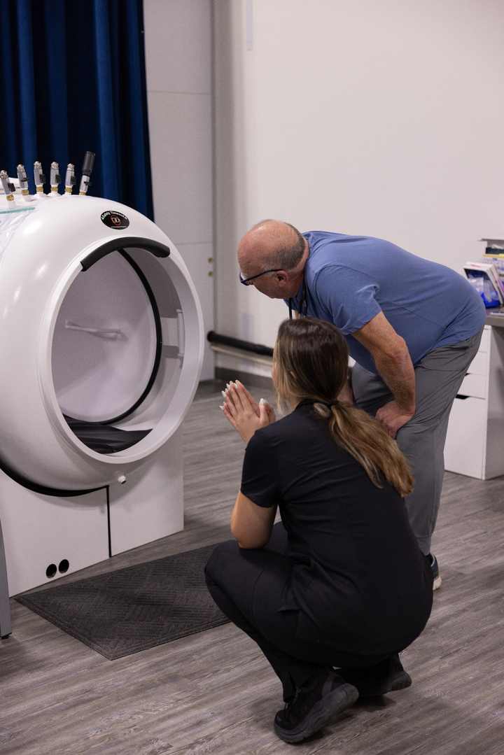 Trainees closely examining the open entry and controls of a hyperbaric chamber