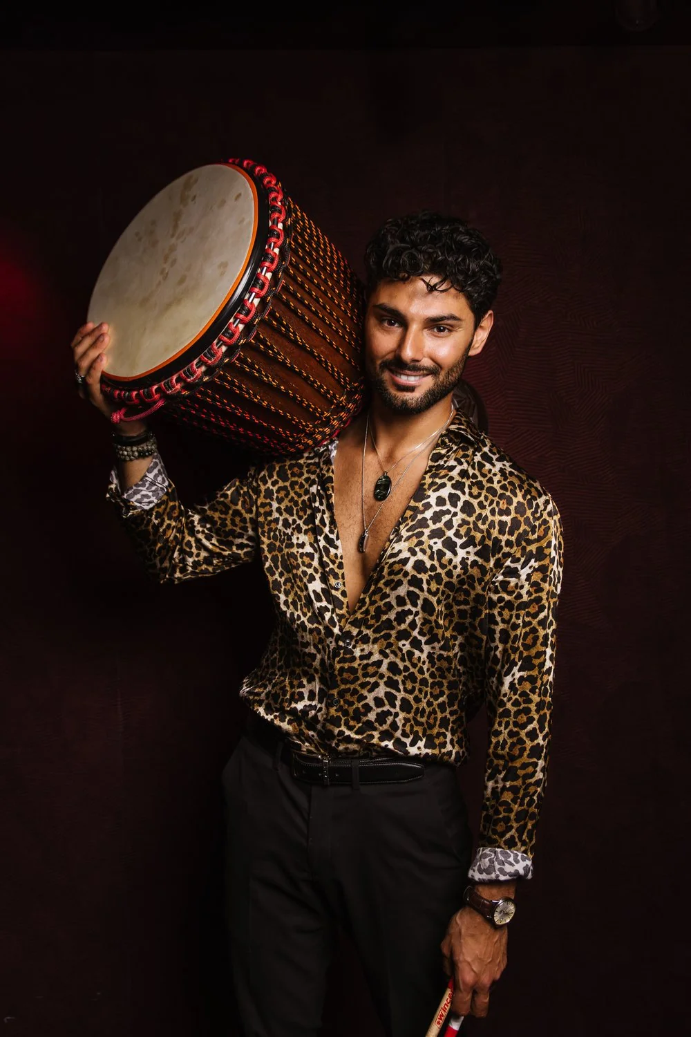 Noa Percu, portrait studio, djembé à l'épaule, chemise léopard