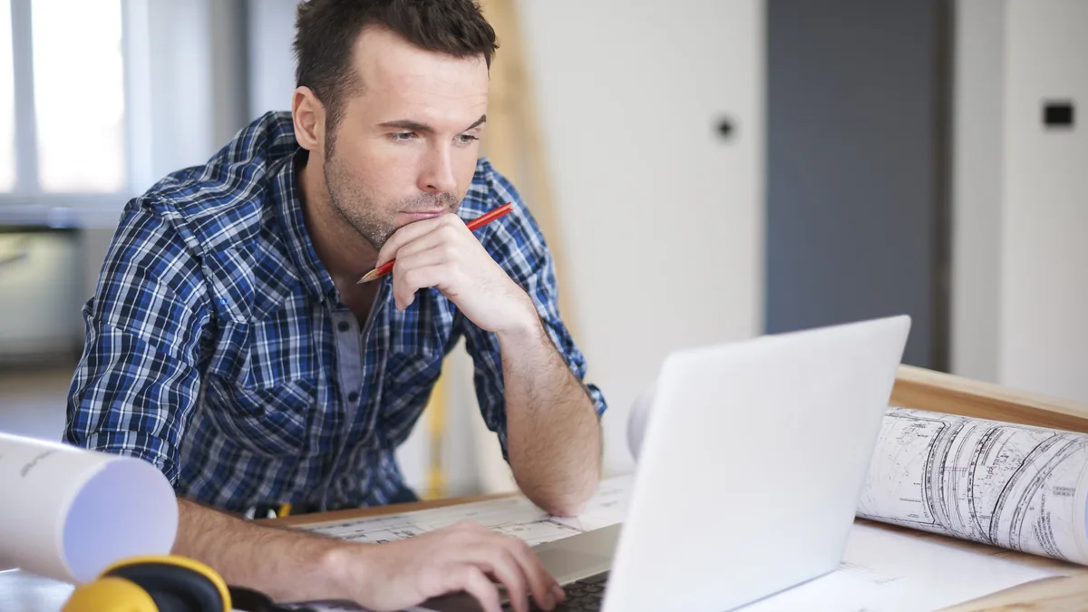 Home service professional organizing work on a laptop.