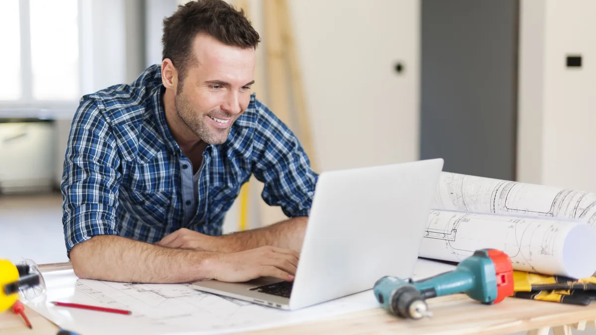 Contractor using a laptop at a home renovation worksite.