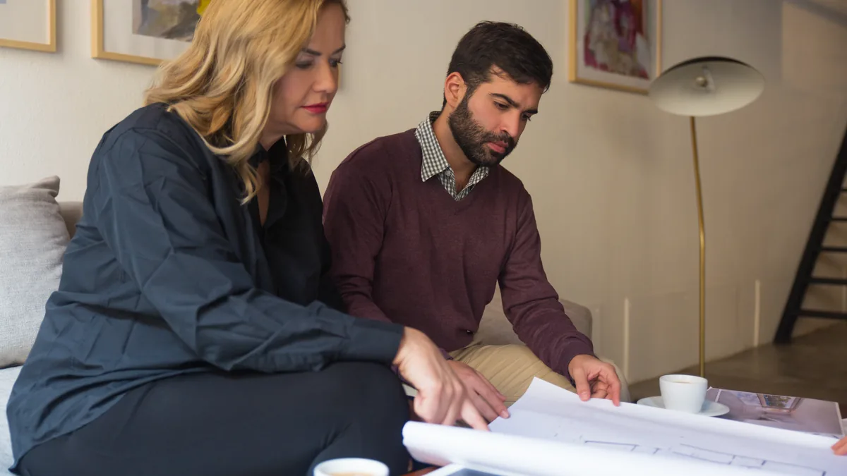 Home service professional and client reviewing plans during a consultation.