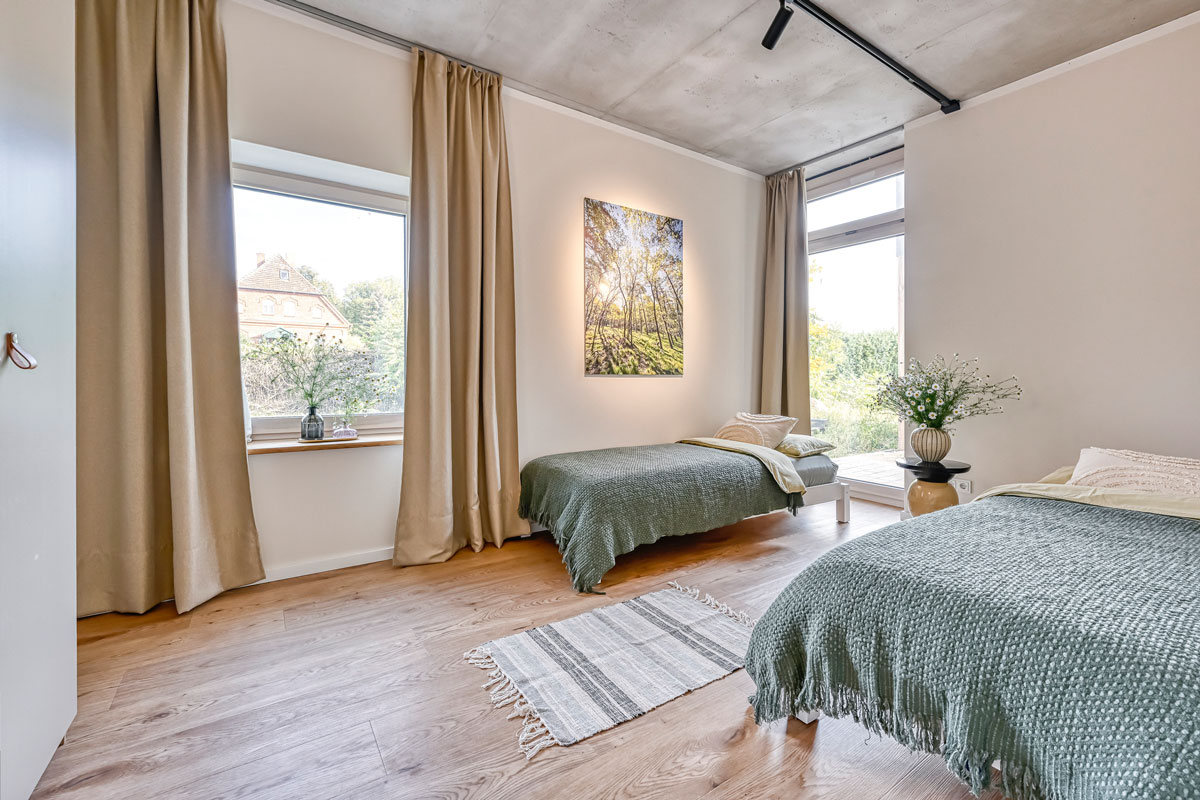 Zimmer mit zwei Betten, grünen Decken und Blick nach draußen