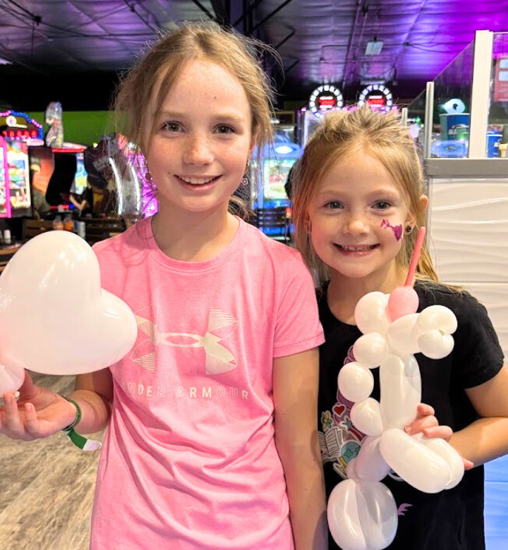 Two girls with balloon animals in Action City at a Dr. Seuss Day party.