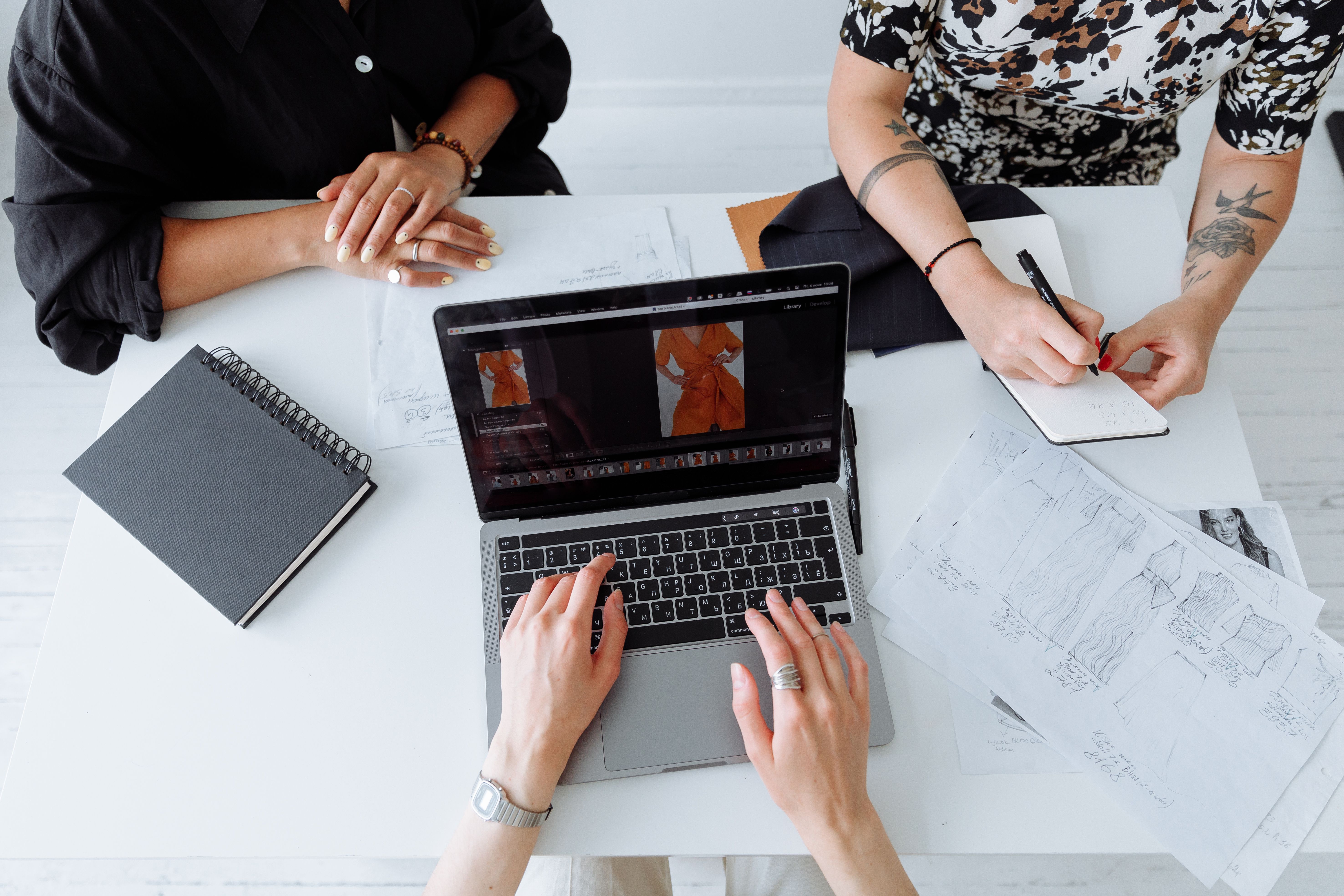 A brand-side designer working at a laptop in a fashion studio, illustrating the audit-ready reporting workflow required for textile EPR compliance.