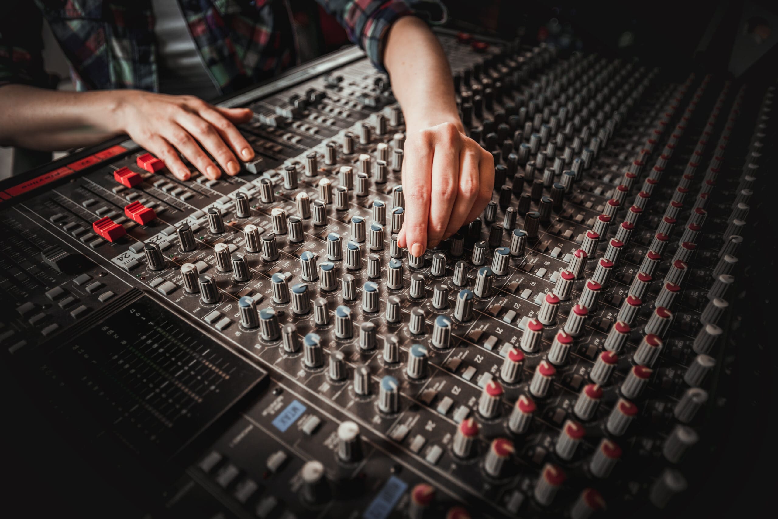 Professional audio engineer working at advanced mixing console in modern studio