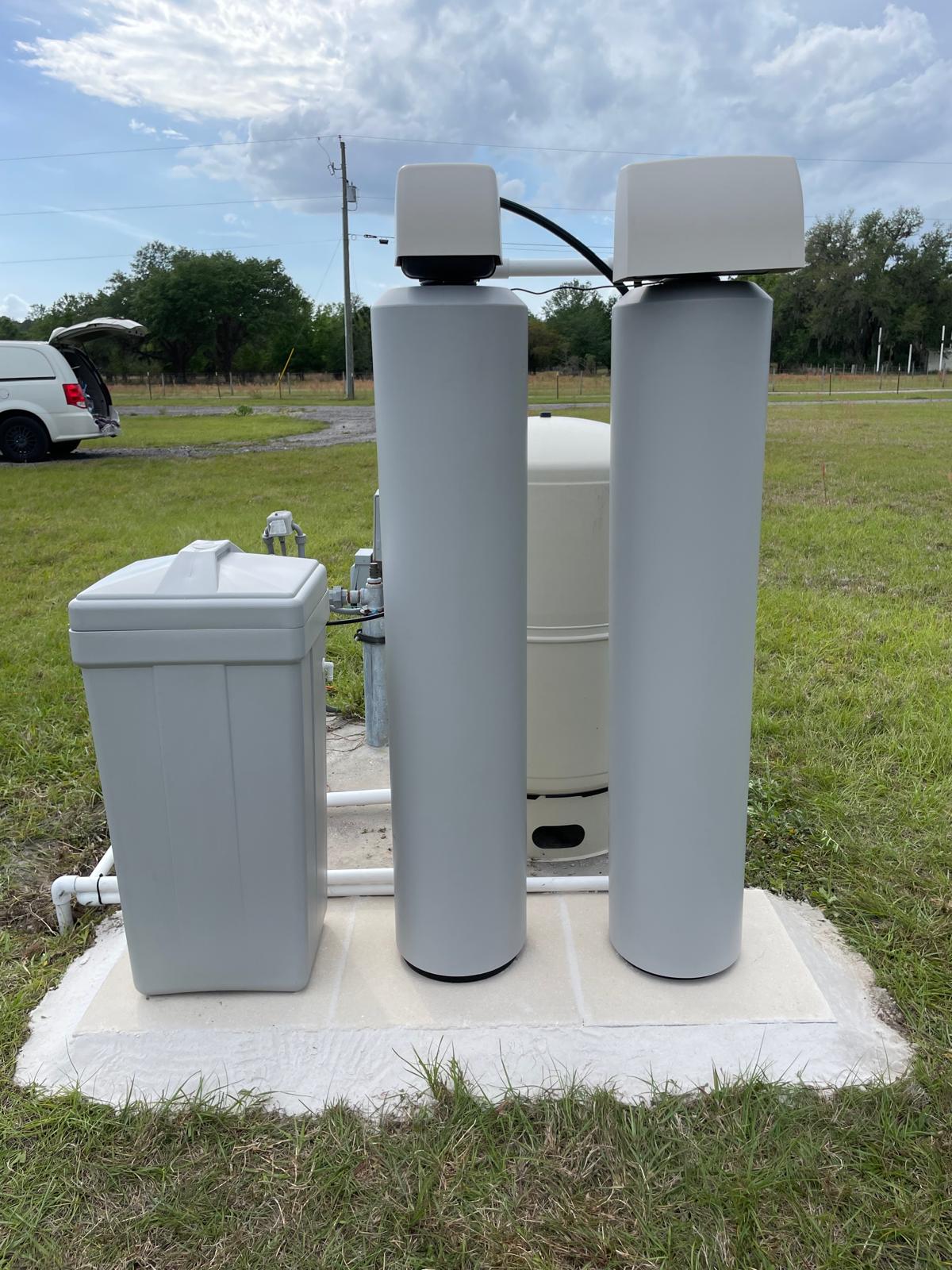 Water treatment technician testing well water quality at an outdoor spigot