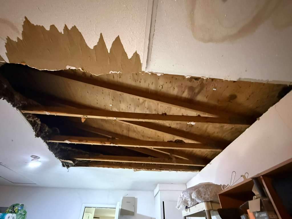 Large opening in interior ceiling exposing wooden joists and overhead framing during water damage investigation in San Antonio TX 78233