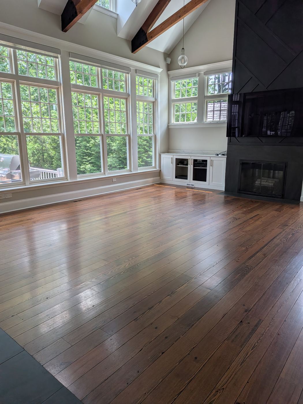 Bright sunroom with clean dark hardwood floors and large windows after cleaning