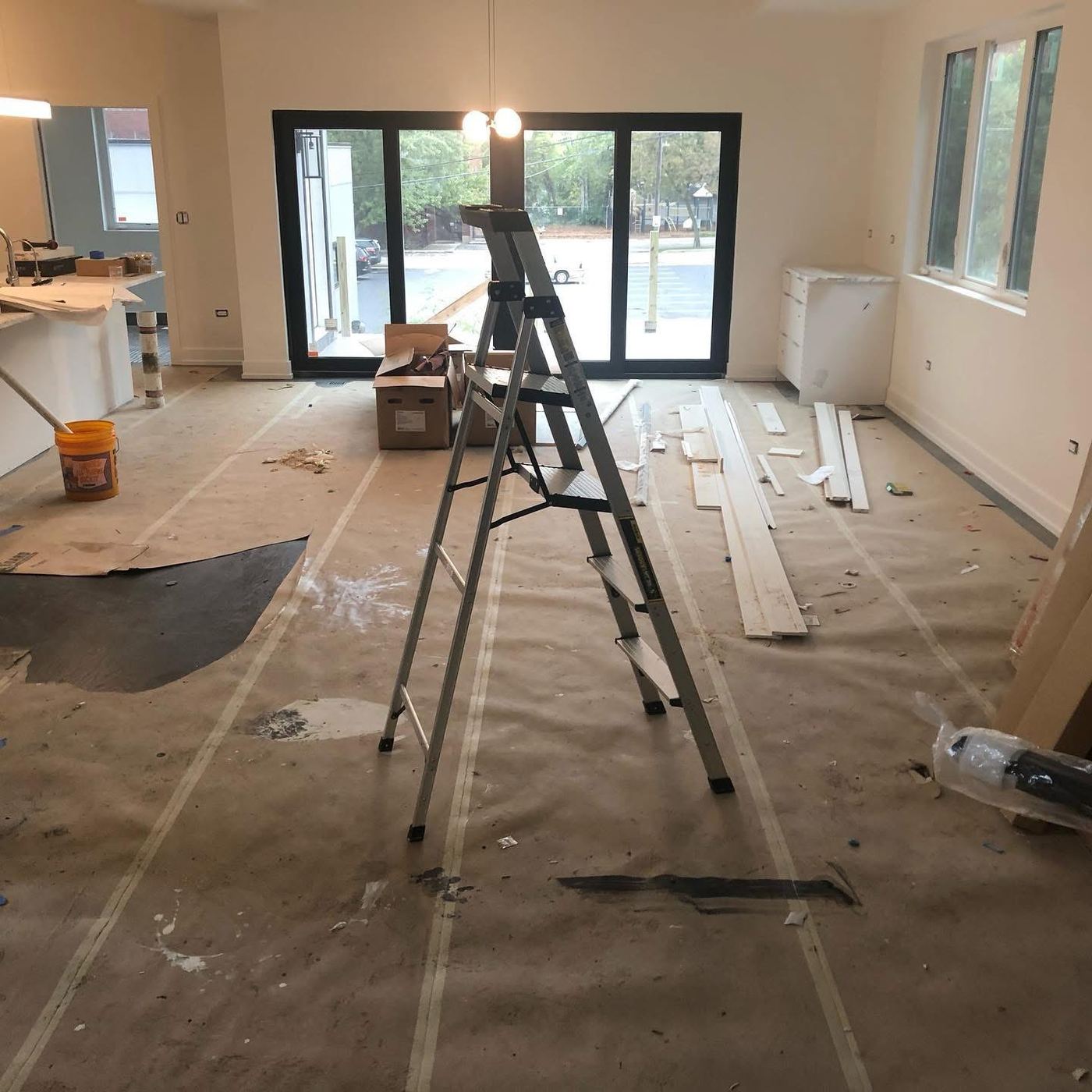 Renovation in progress with floor protection and ladder before post-construction cleanup