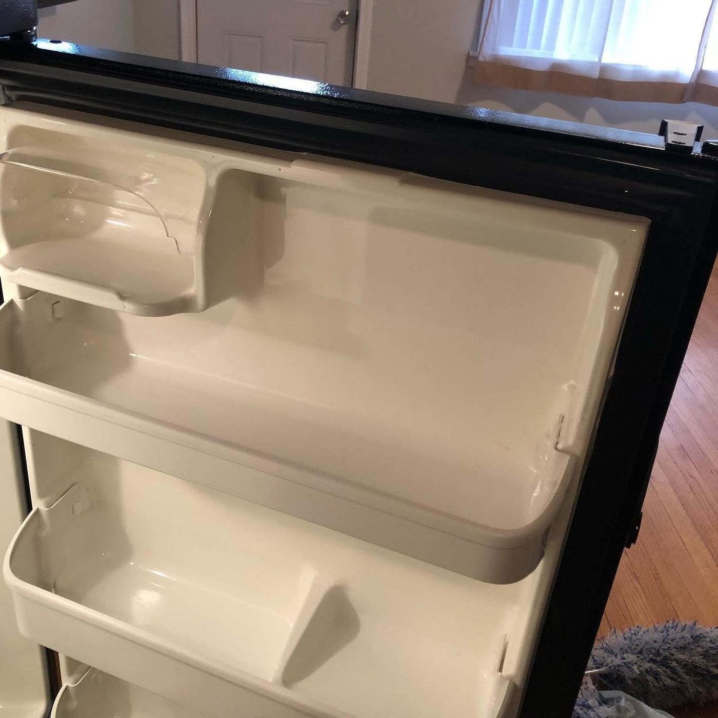 Refrigerator door shelves wiped clean during move-out cleaning
