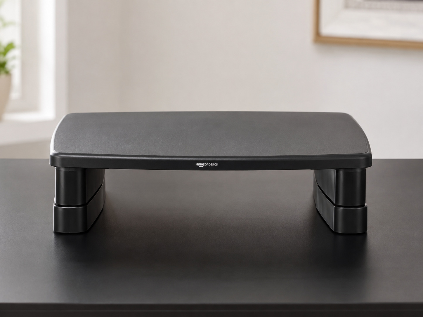 Black monitor riser on a black desk showing the tapered profile. Black monitor riser on a black desk showing the tapered profile.