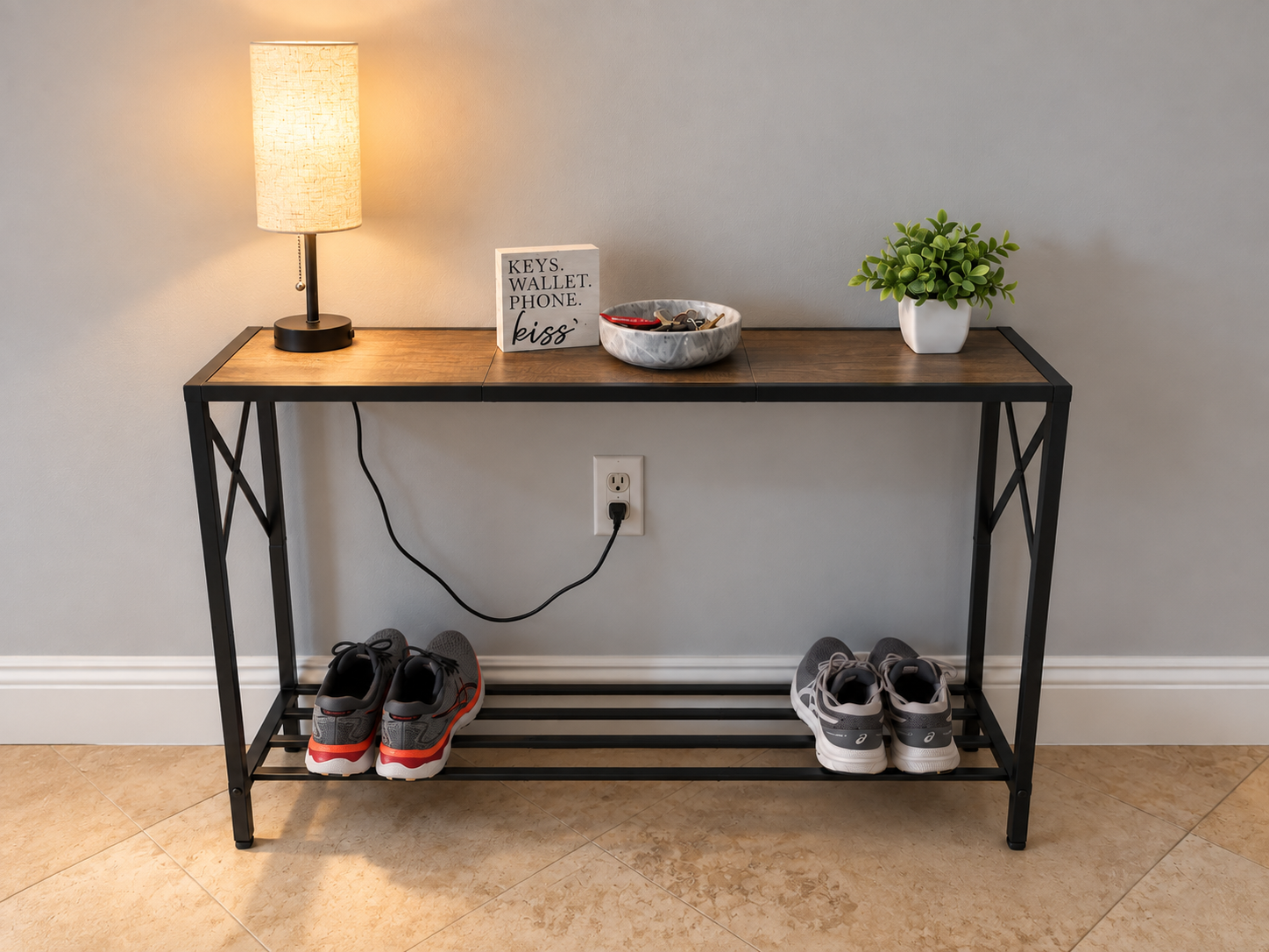 Small condo entryway with a two-tier console table, table lamp, marble key bowl, decorative sign and faux plant.
