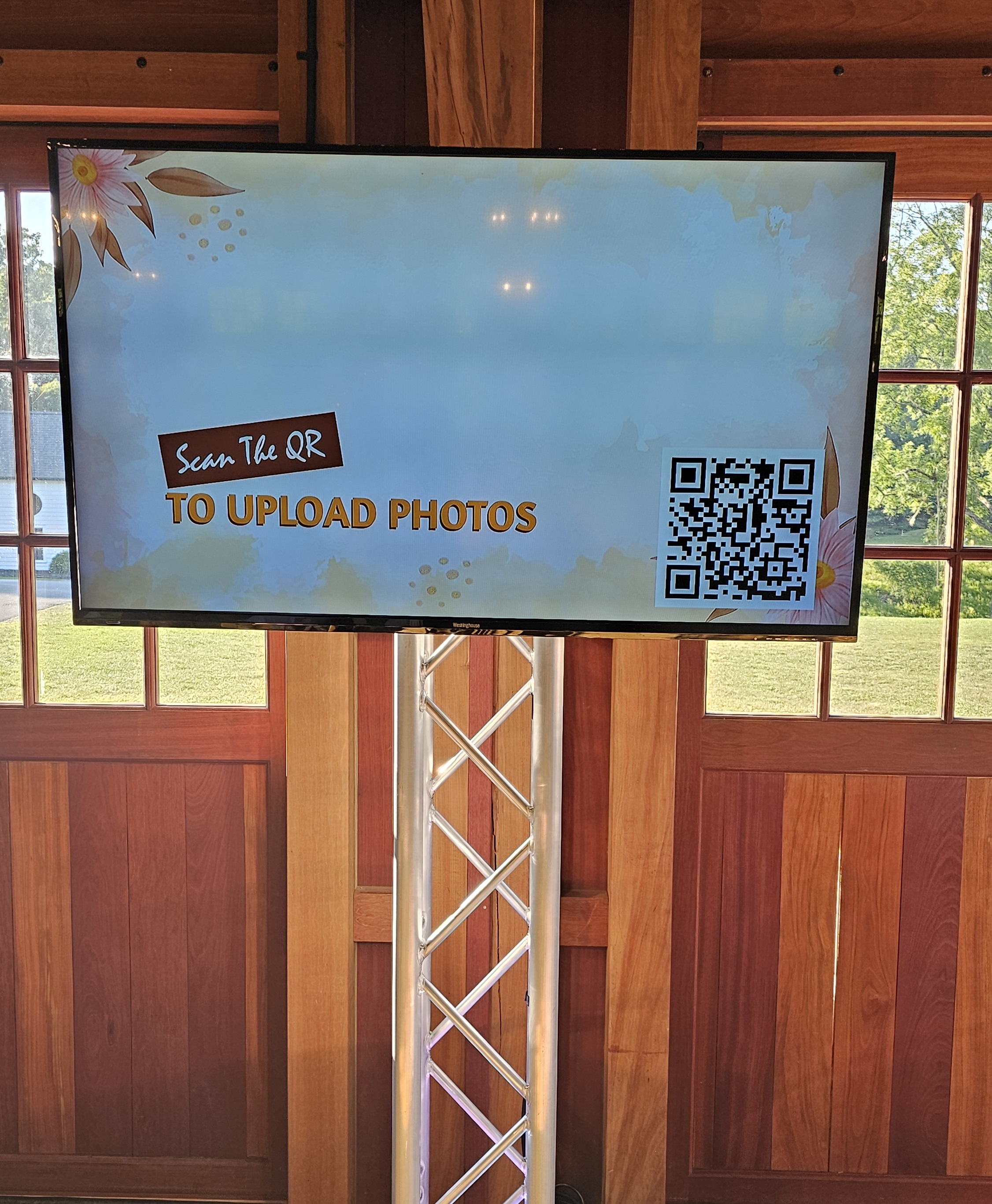 TV on truss showing a scan-to-upload QR code so guests can share their photos