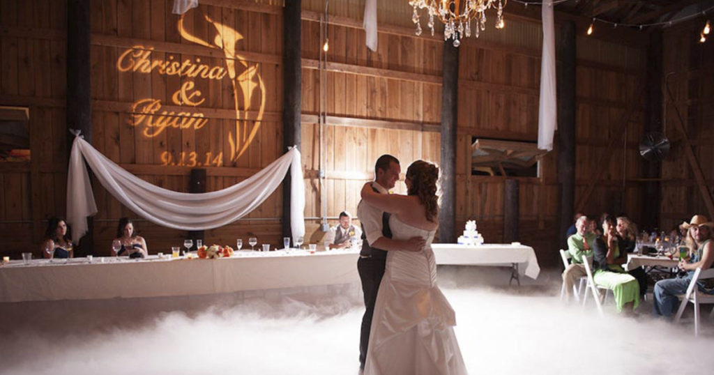 Couple's names and wedding date projected in light on a barn wall during their first dance