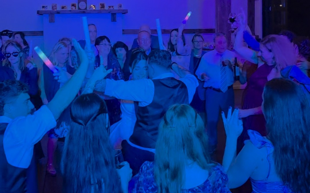 Packed dance floor with glow sticks at a wedding reception