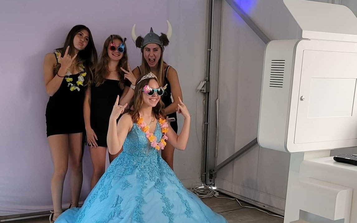 Sweet 16 guest of honor and friends posing with props in front of the photo booth