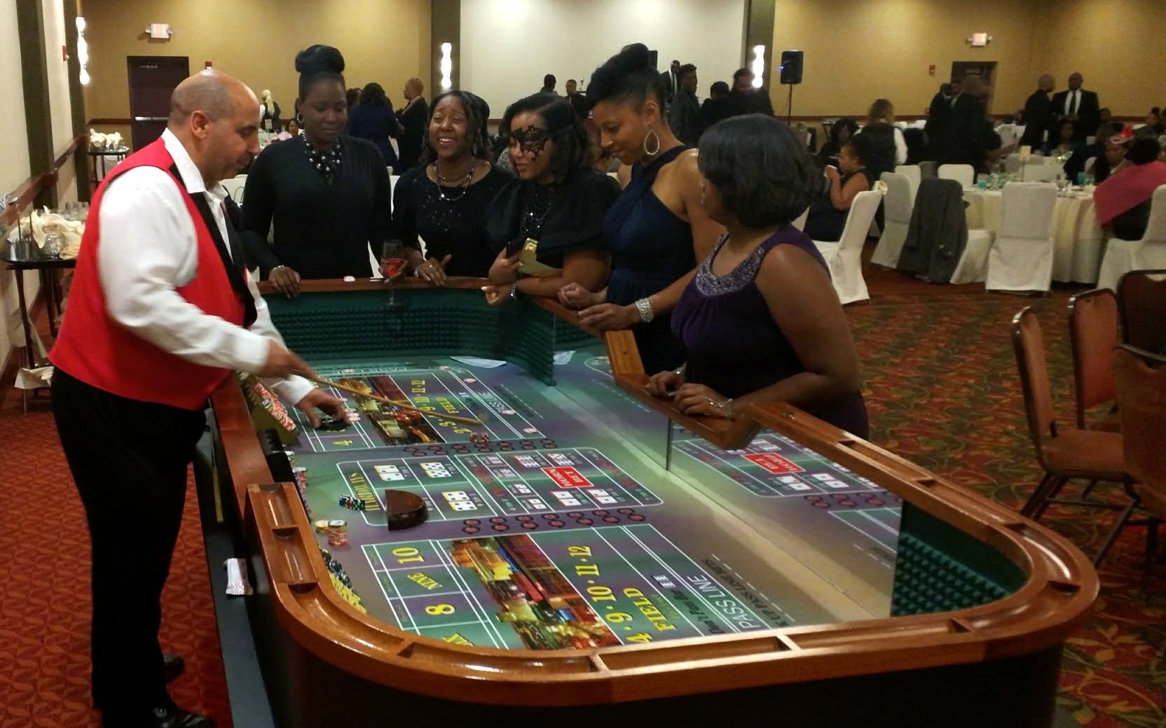 Guests laughing around a craps table with a professional dealer at a corporate gala casino night