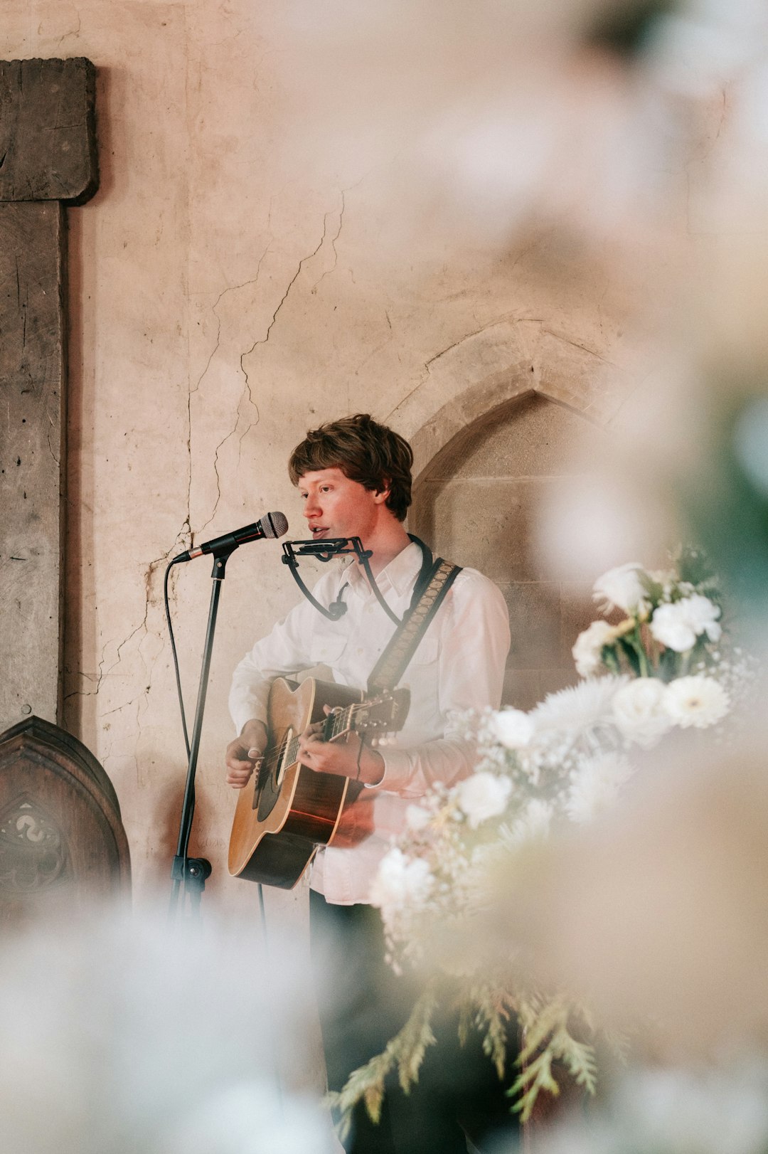 Singer with an acoustic guitar performing into a microphone at a wedding ceremony
