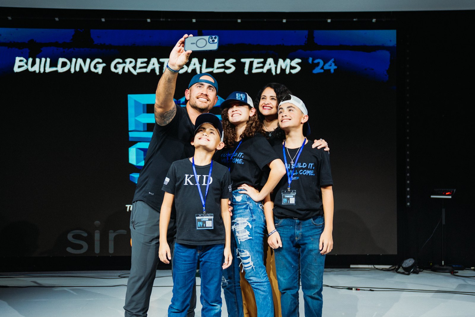 Doug Mitchell taking a selfie with his family on stage at Building Great Sales Teams 2024