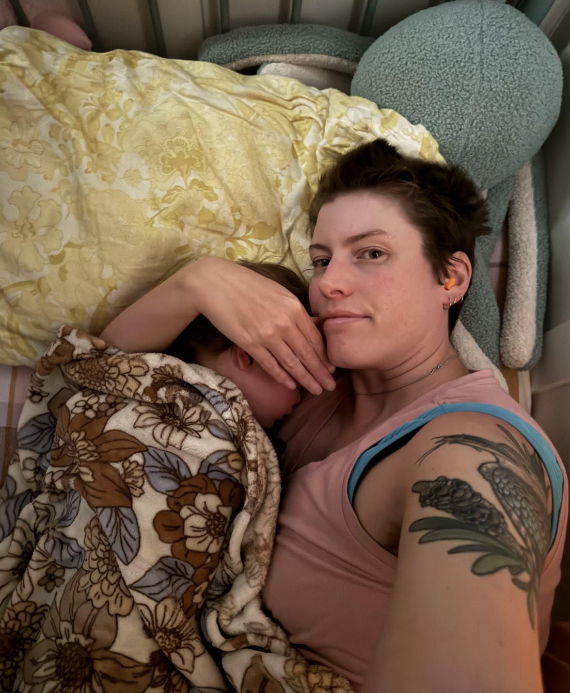 an adult with short hair cuddling a toddler to sleep. A hand is over the toddlers face to preserve privacy. an adult with short hair cuddling a toddler to sleep. A hand is over the toddlers face to preserve privacy.