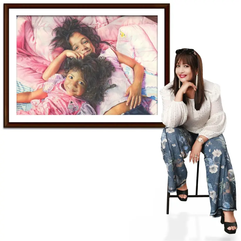 Meeta seated beside one of her framed watercolor paintings