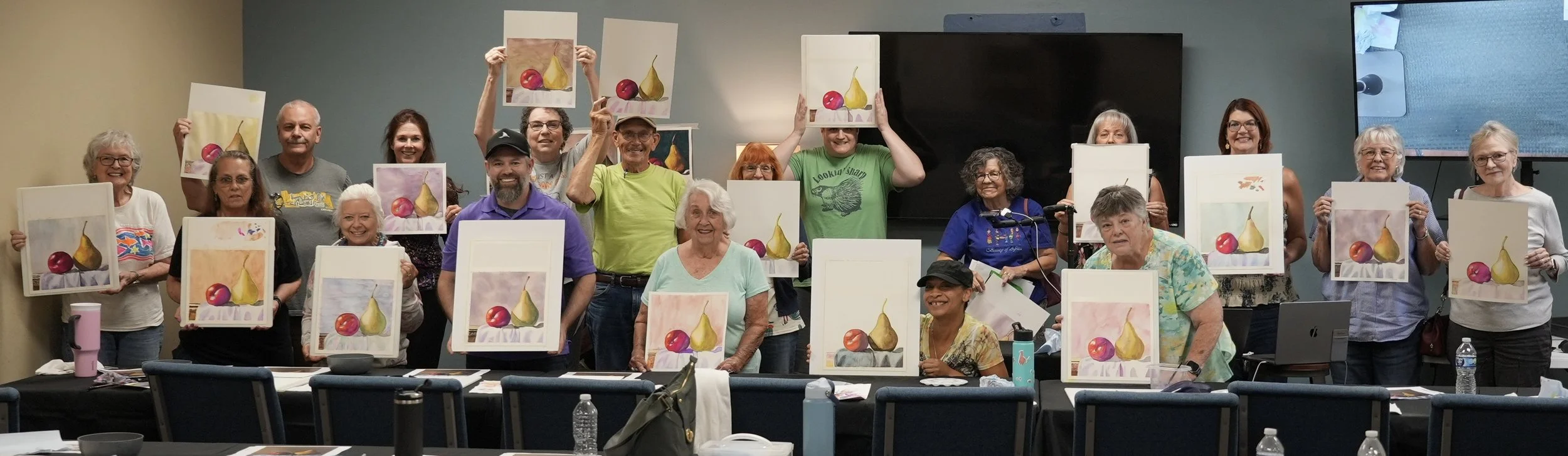 More than twenty of Caleb Grimes&rsquo;s workshop students holding their finished pear and plum watercolor paintings